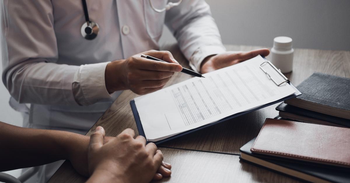 Doctor is writing the appointment letter to the patient at the clinic. - stock photo