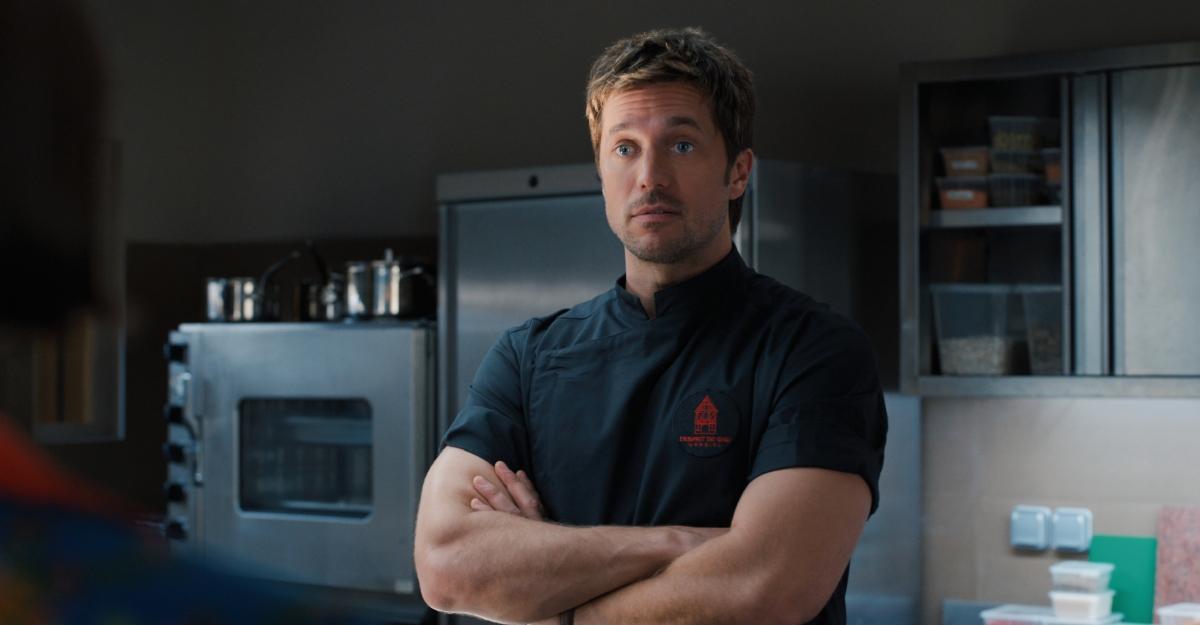 Gabriel crosses his arms in a kitchen in Emily in Paris Season 5.