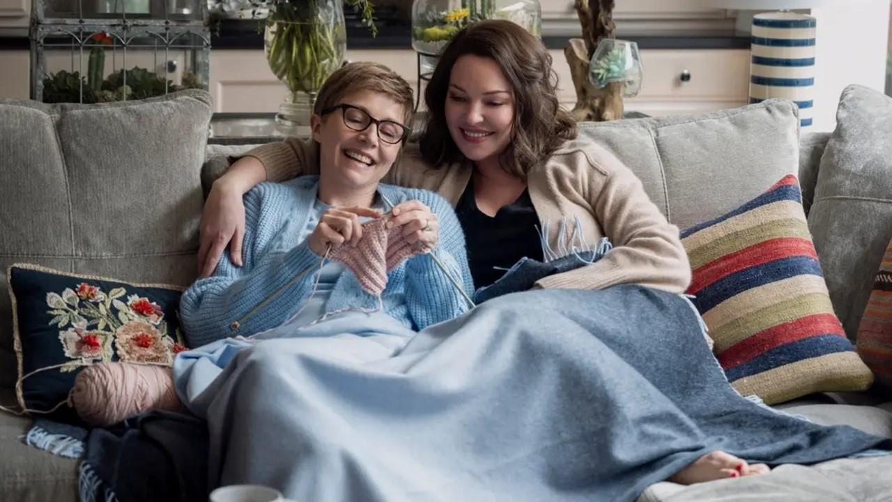 Kate knitting and sitting on a couch with Tully