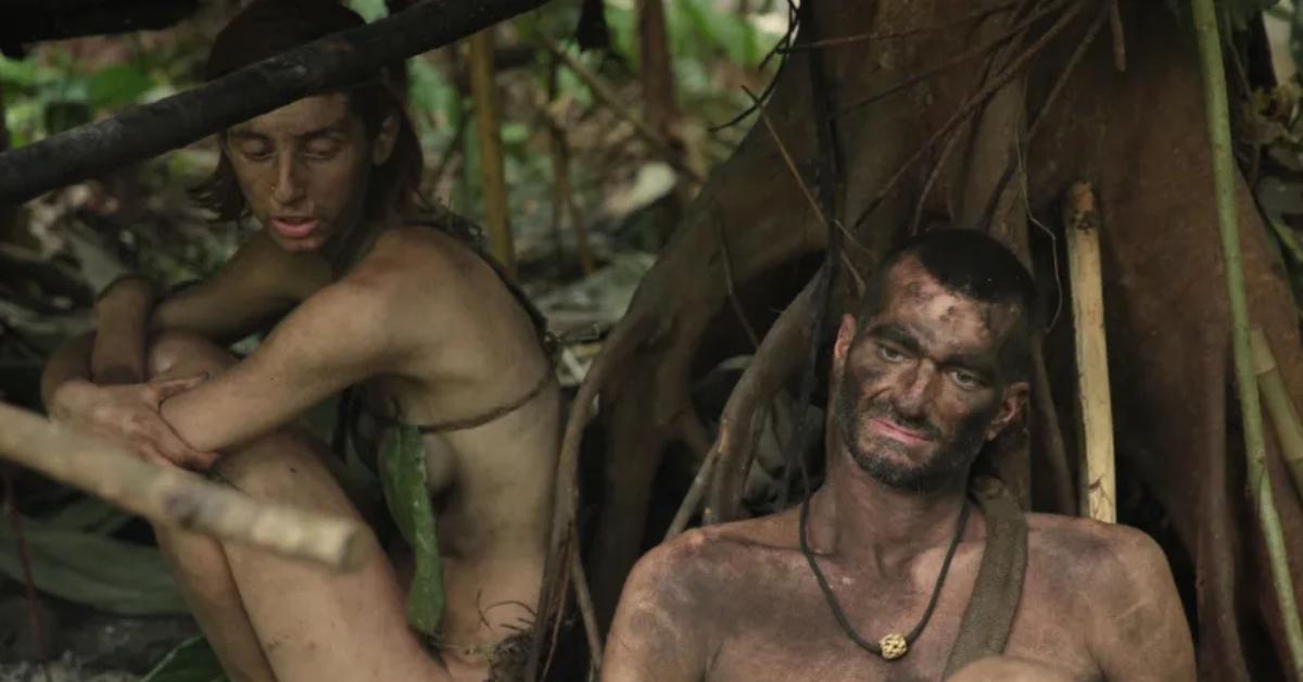 'Naked and Afraid' contestants sitting down, covered in mud.