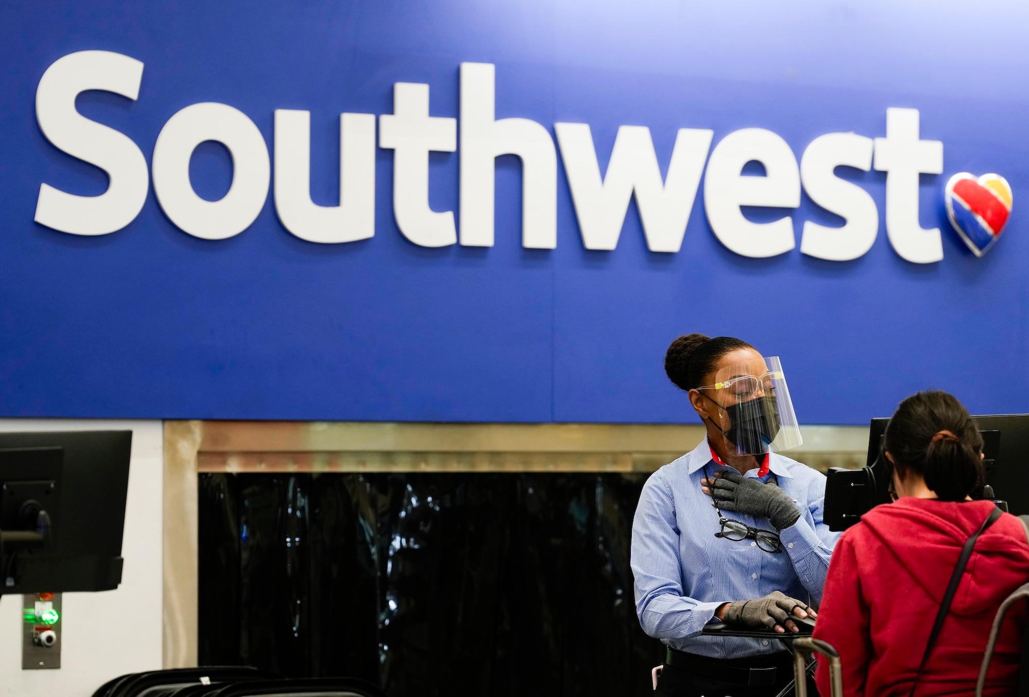 A woman wears a face shield as she checks in passengers for Southwest Airlines