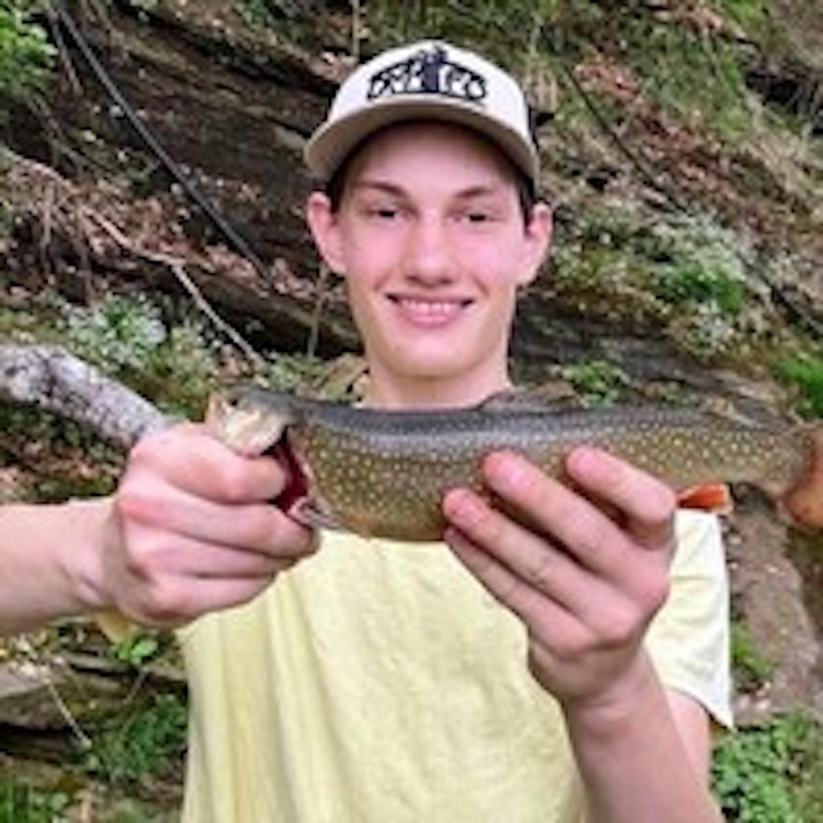 Olivia Plath's brother Micah Meggs holding a fish and smiling