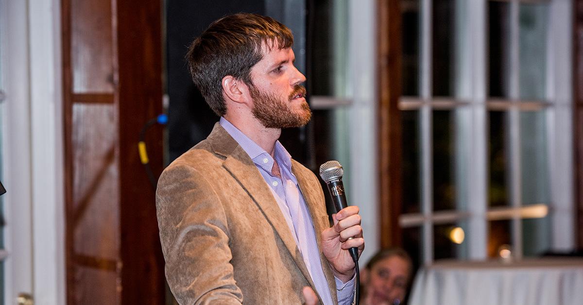 Brandon Stanton speaking at an event in 2016 in a suit jacket. 