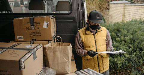 A delivery driver stands with packages
