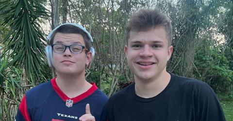 Sketch wears headphones while standing next to a friend