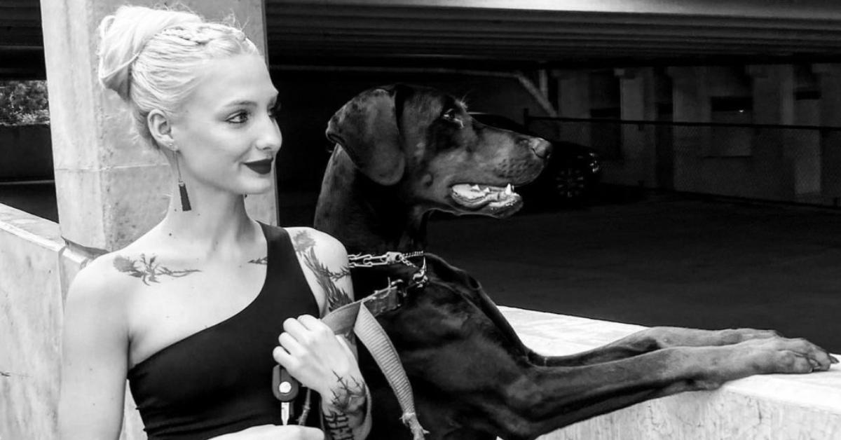 Moriah Plath showing off her tattoos standing beside her dog.