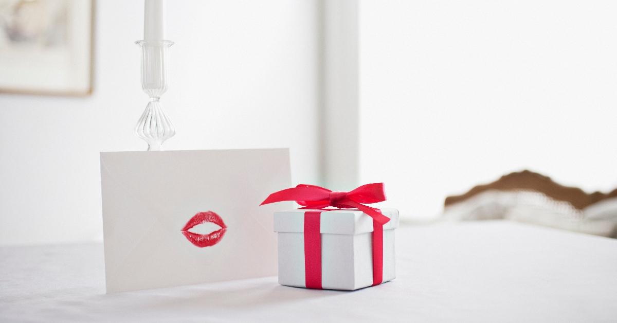 Gift box with ribbon and card with lipstick kiss on desk - stock photo