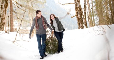 couple pulling christmas tree through snow