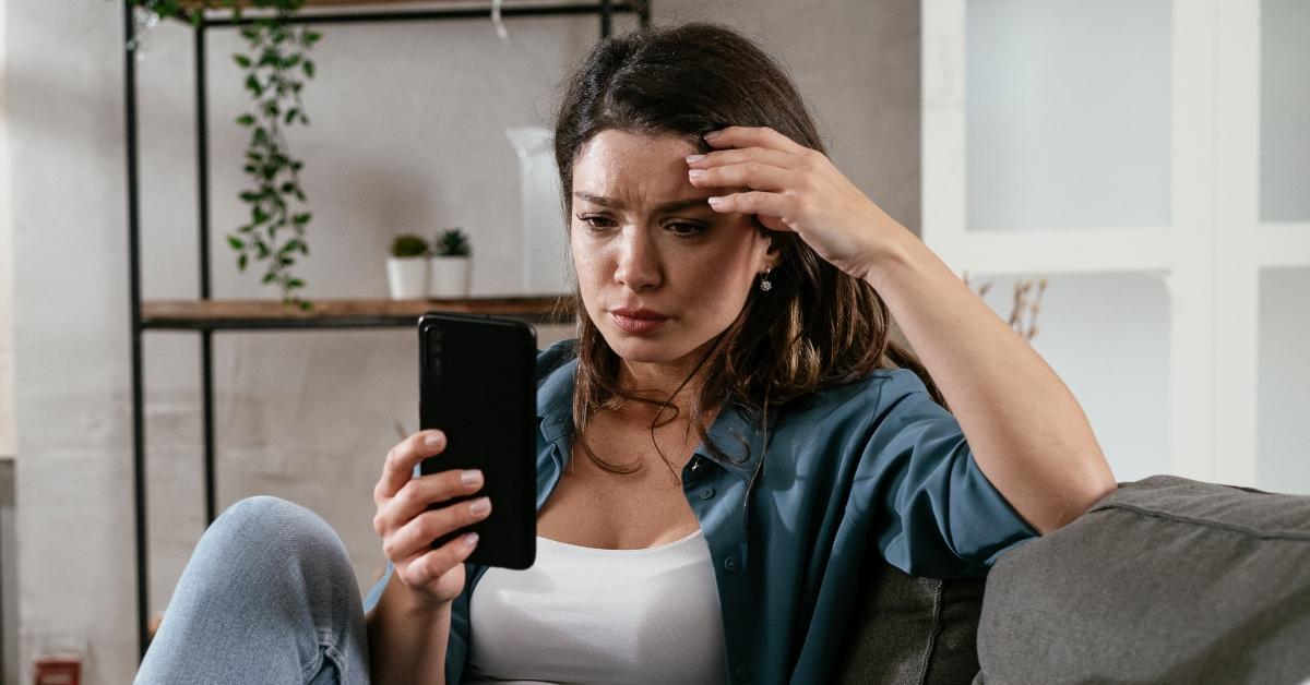 Sad woman sitting on the couch, using the phone