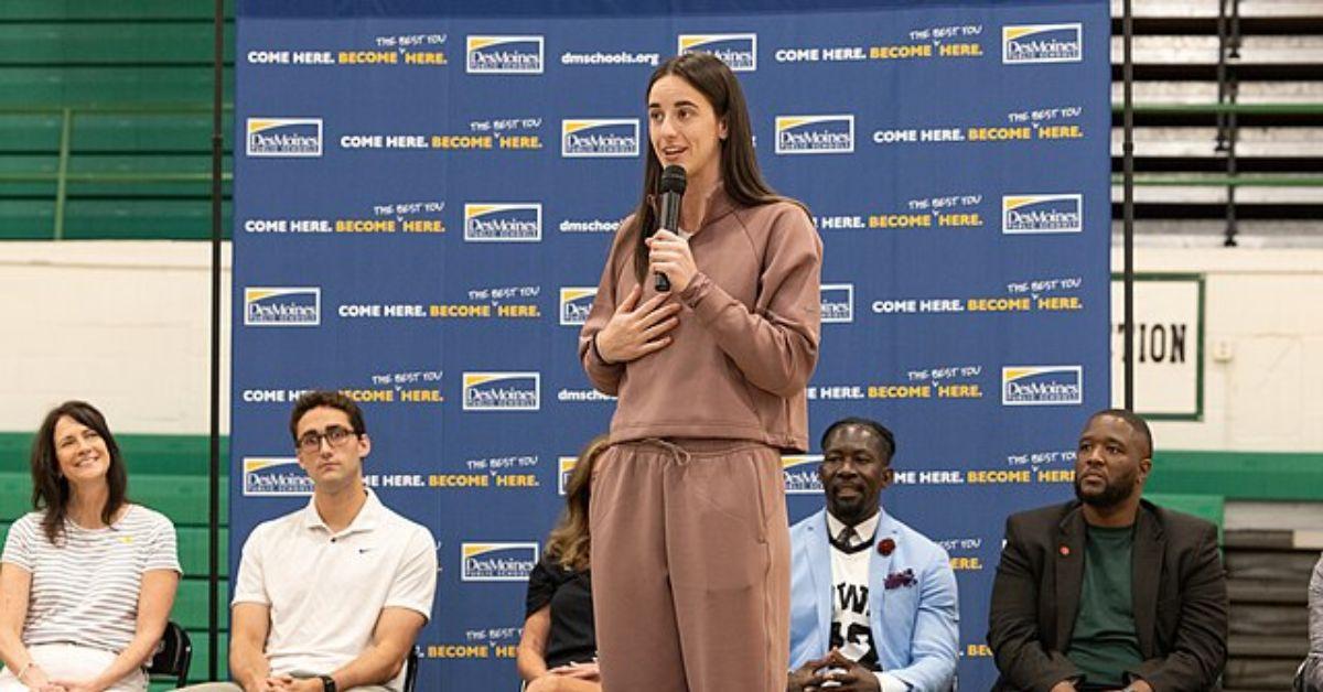 Caitlin Clark holding a mic and speaking.
