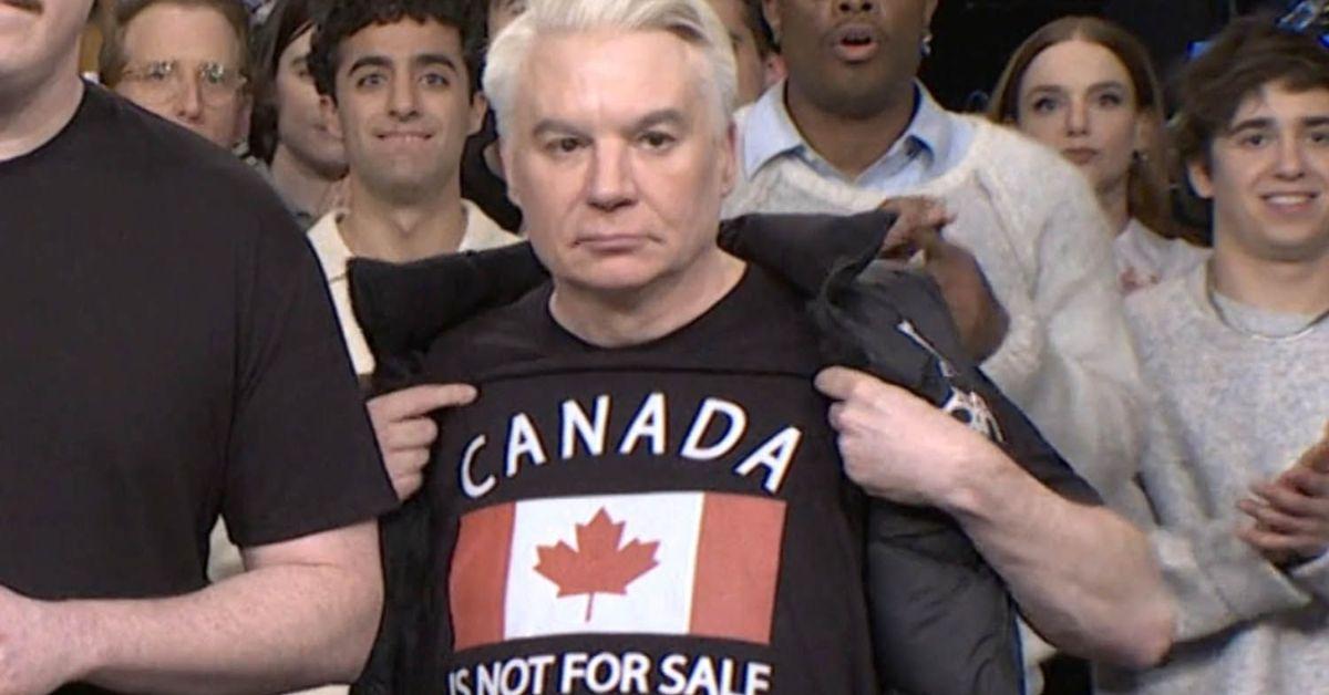 Mike Myers holding up a Canada is Not for Sale shirt. 