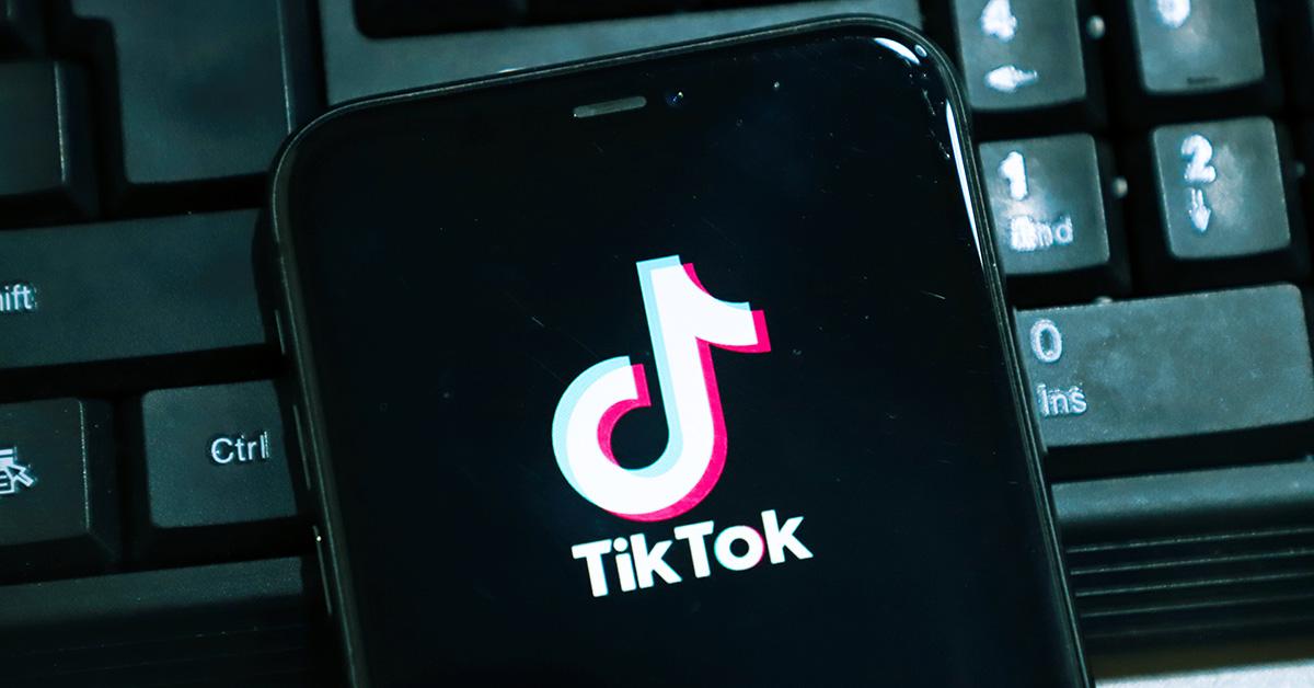 The TikTok logo on a phone with a computer keyboard behind it. 