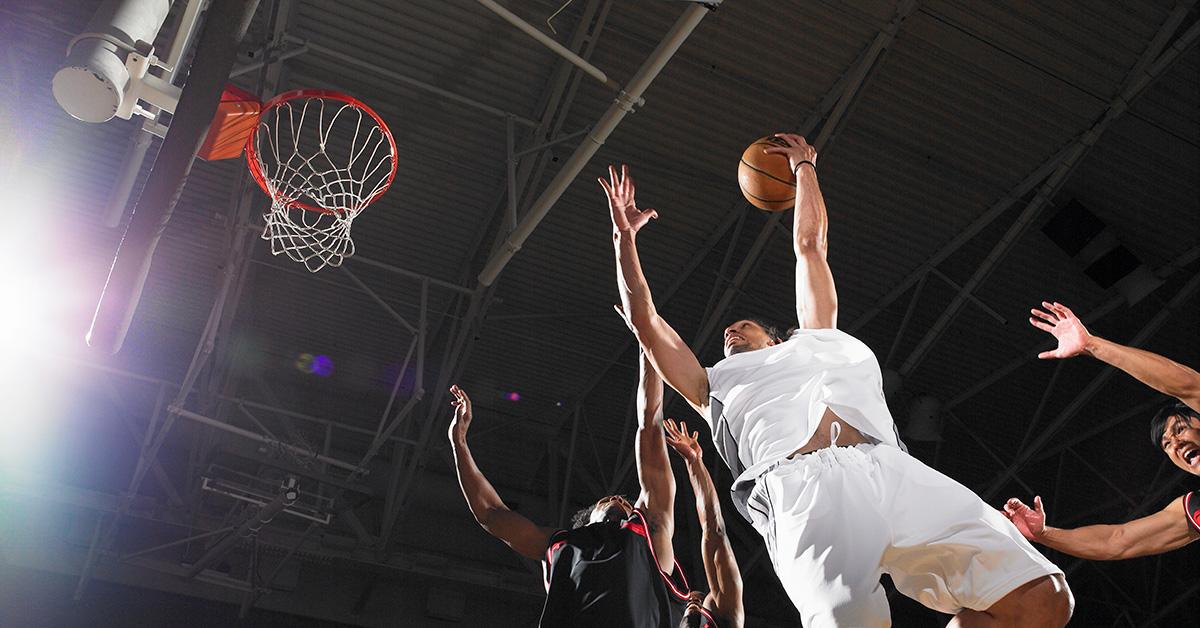 A man goes up for a dunk in a game of basketball. 