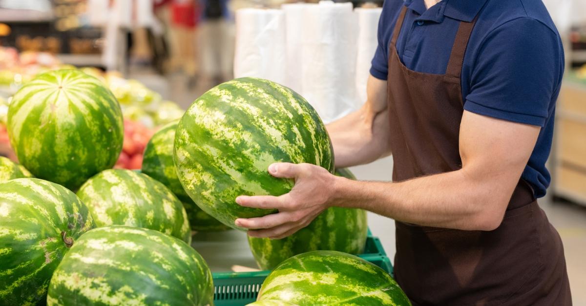 grocery store worker setting out watermelons