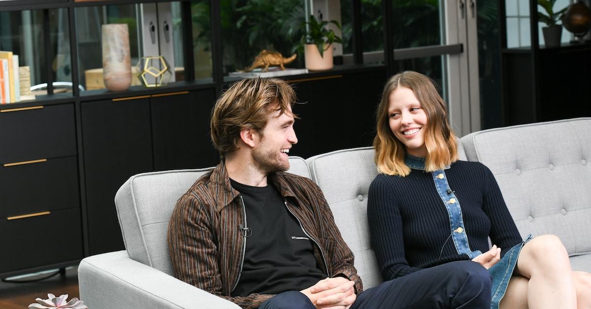 Robert Pattinson and Mia Goth sitting on a couch