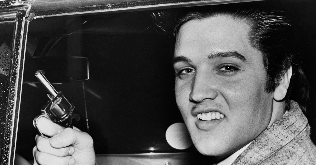 Elvis Presley brandishing a small pistol in black and white