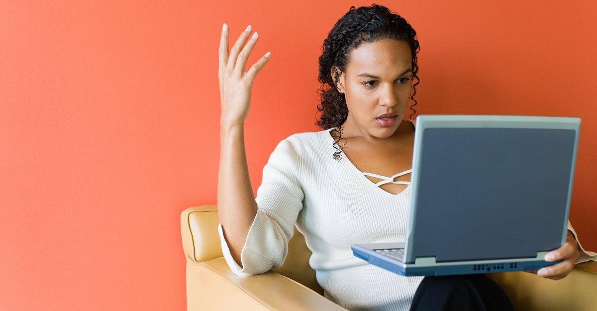 A woman looks annoyed at her laptop.