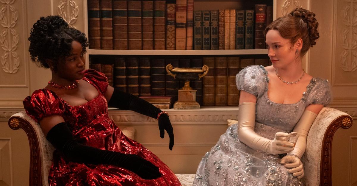 Michaela and Francesca look at each other while sitting on a fancy couch.