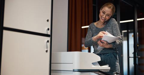 A woman smiling near a copy machine.