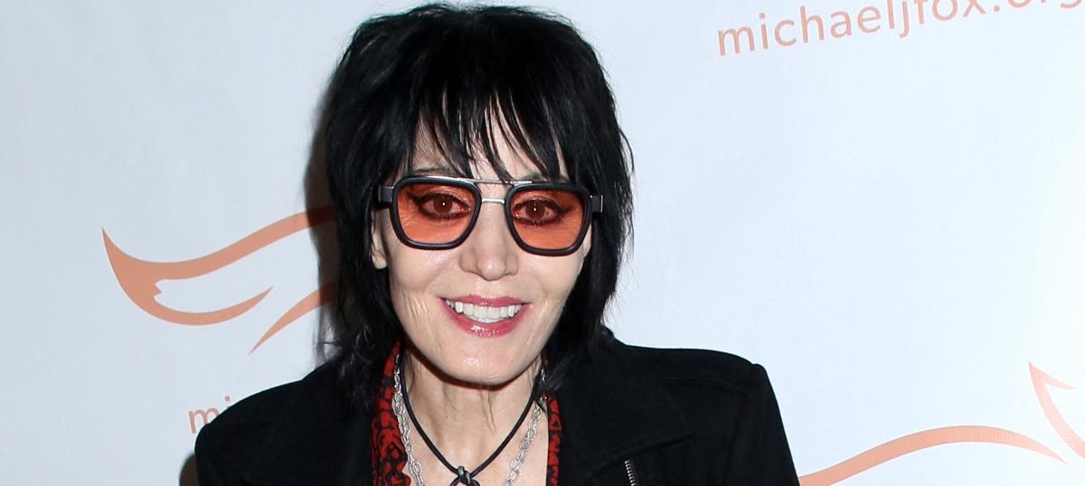 Joan Jett wearing red-tinted sunglasses and pinkish-red lipstick