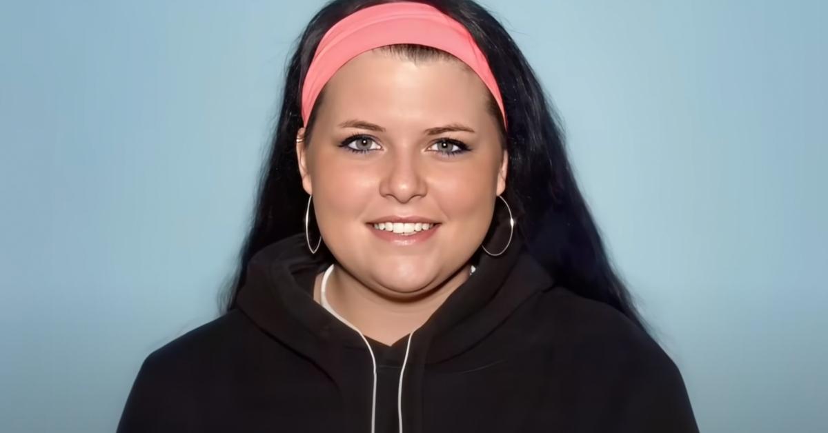 Kirstie Flood smiles wearing a black hoodie and pink headband