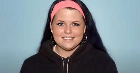 Kirstie Flood smiles wearing a black hoodie and pink headband