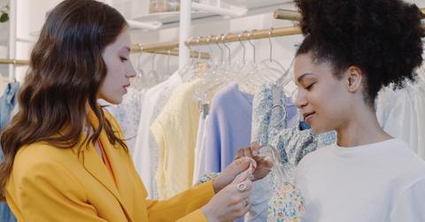 Two women in fitting room of clothing store.