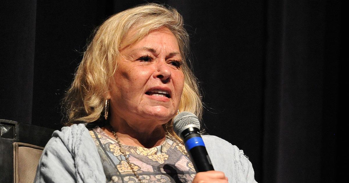 Roseanne Barr holding a microphone onstage. 