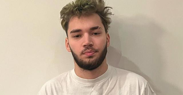 Adin Ross with a beard and a white t-shirt.