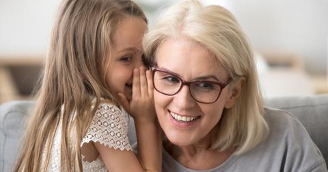 cute little granddaughter whispering in ear telling secret to grandma picture id