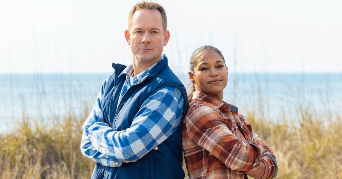 Brian and Mika Kleinschmidt pose back to back on a beachfront