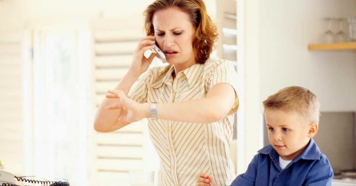 stressed mom with young kid, looking at her watch