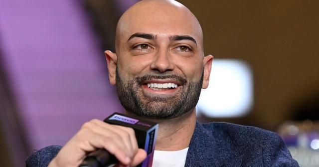 John Fuda holding a microphone and smiling