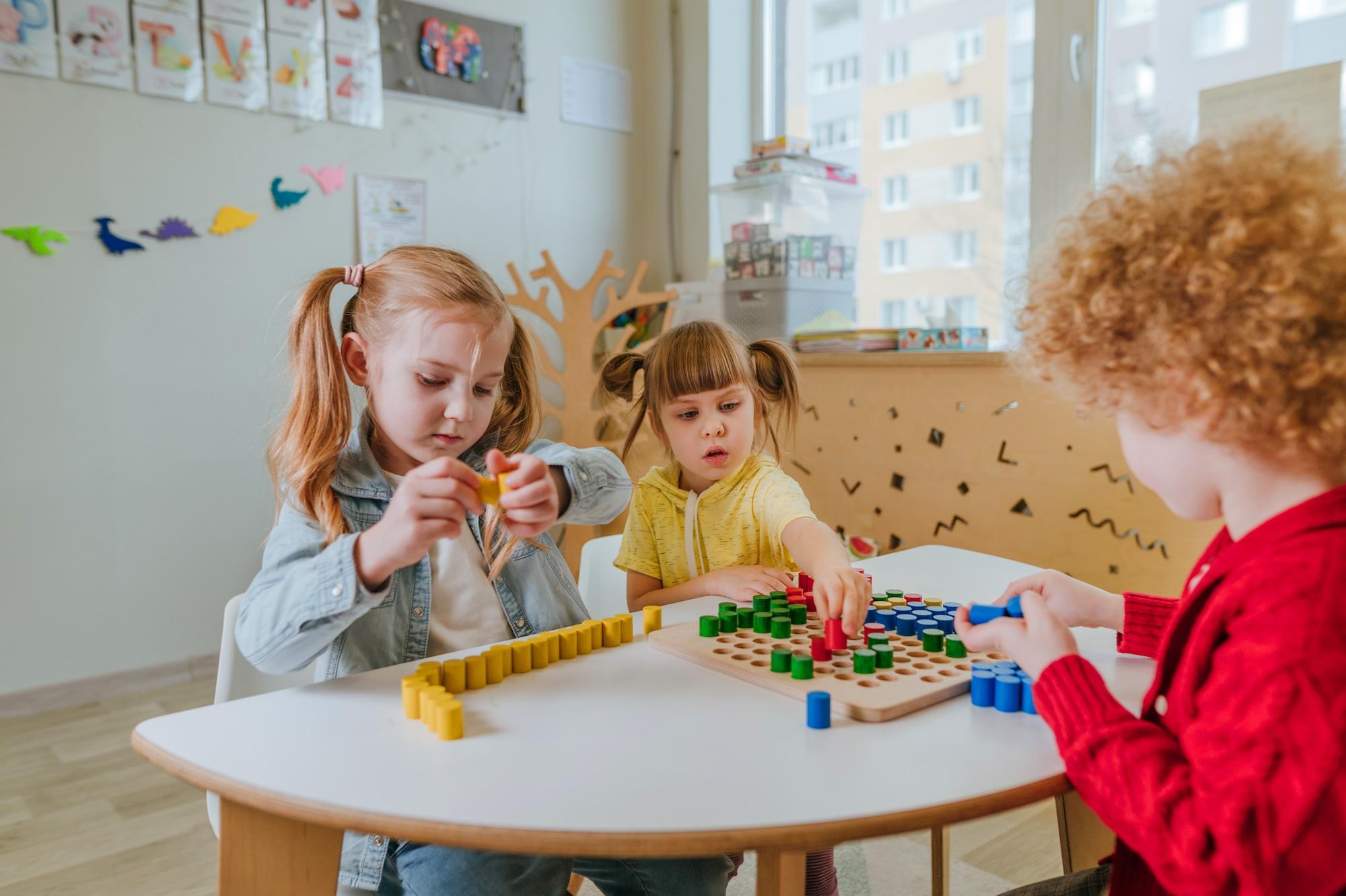 Preschool students playing with wooden mosaic in kindergarten