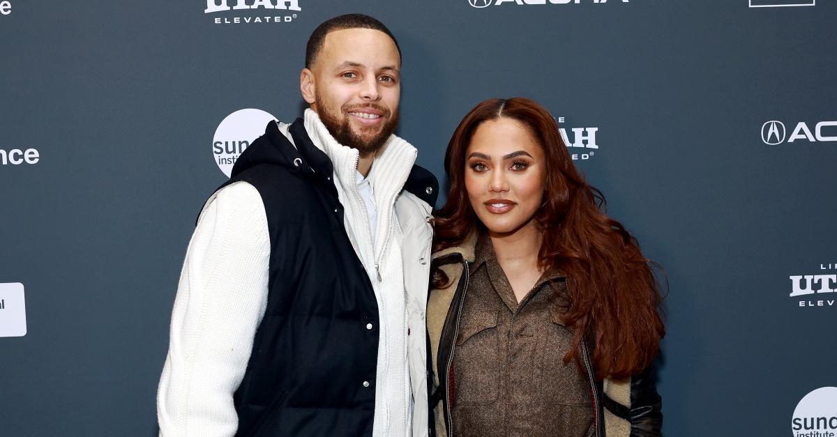 Steph Curry wears white jacket and black vest, Ayesha Curry wears a brown top and jacket and smile at the 2023 Sundance Festival.