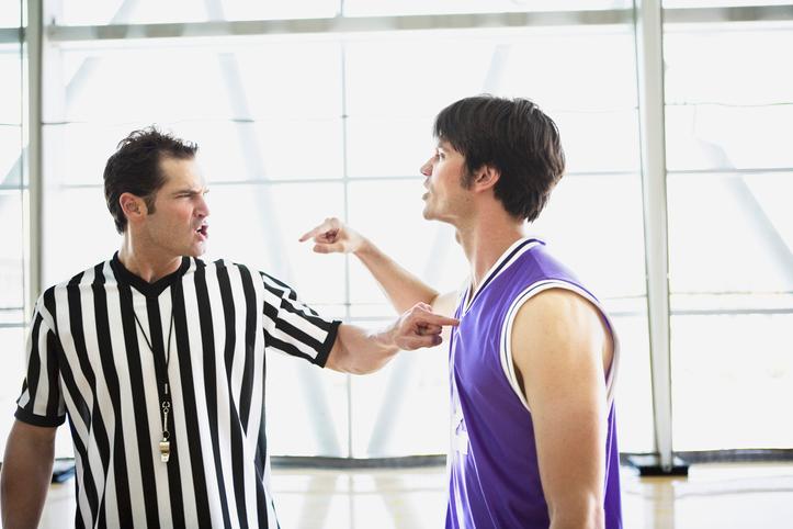 A basketball player and referee are seen in an on-court argument.