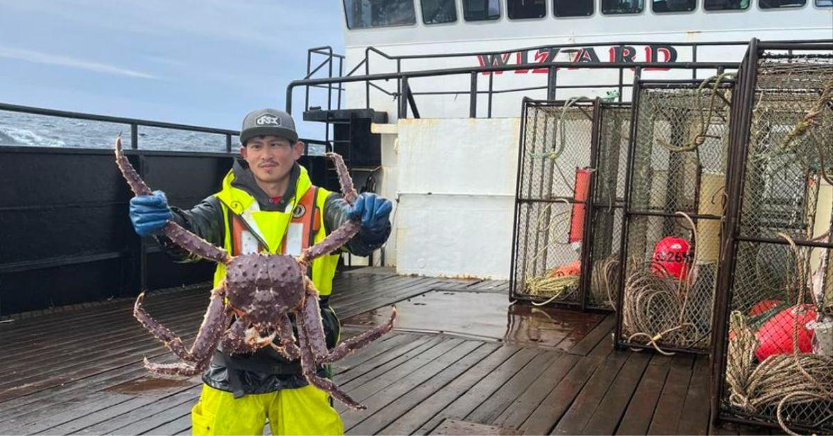 Oj Ganuelas poses holding a giant king crab on the F/V Wizard