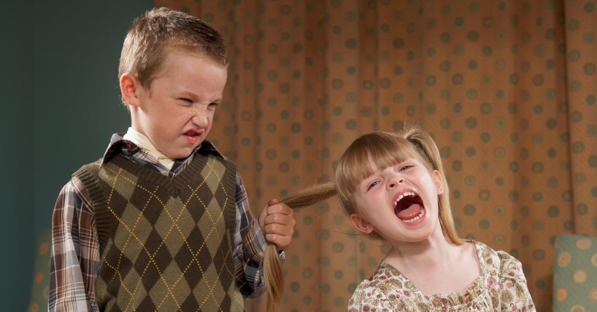 A young boy pulls a little girl's ponytail.