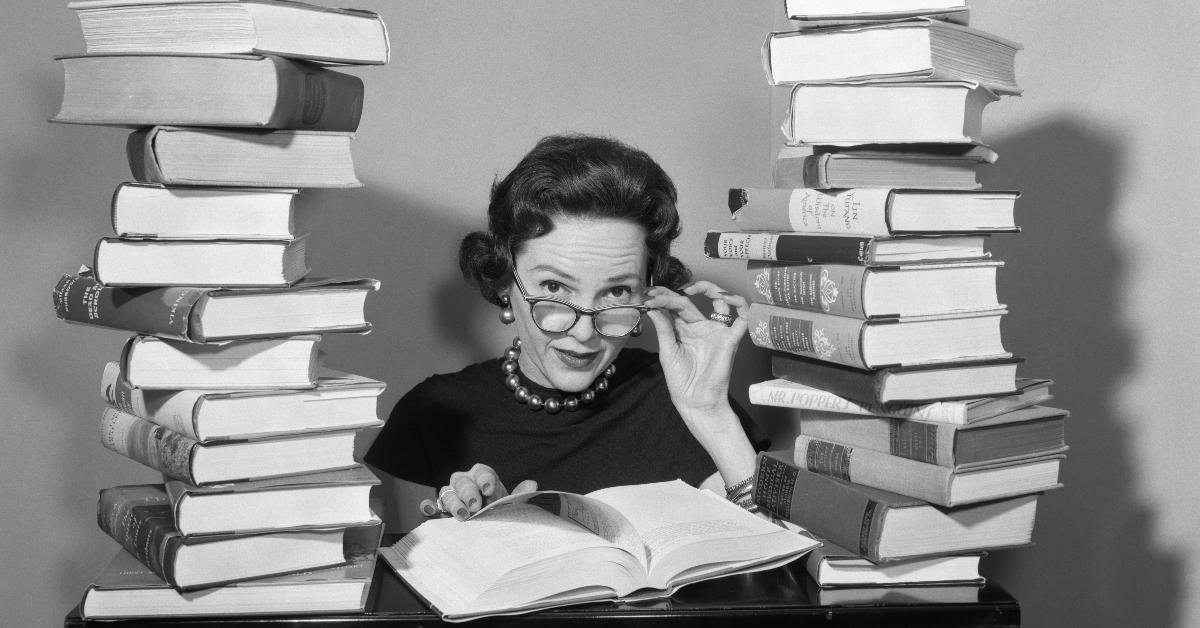 A woman sits between two stacks of books