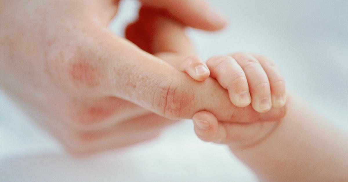 A baby's hand holding a man's finger.