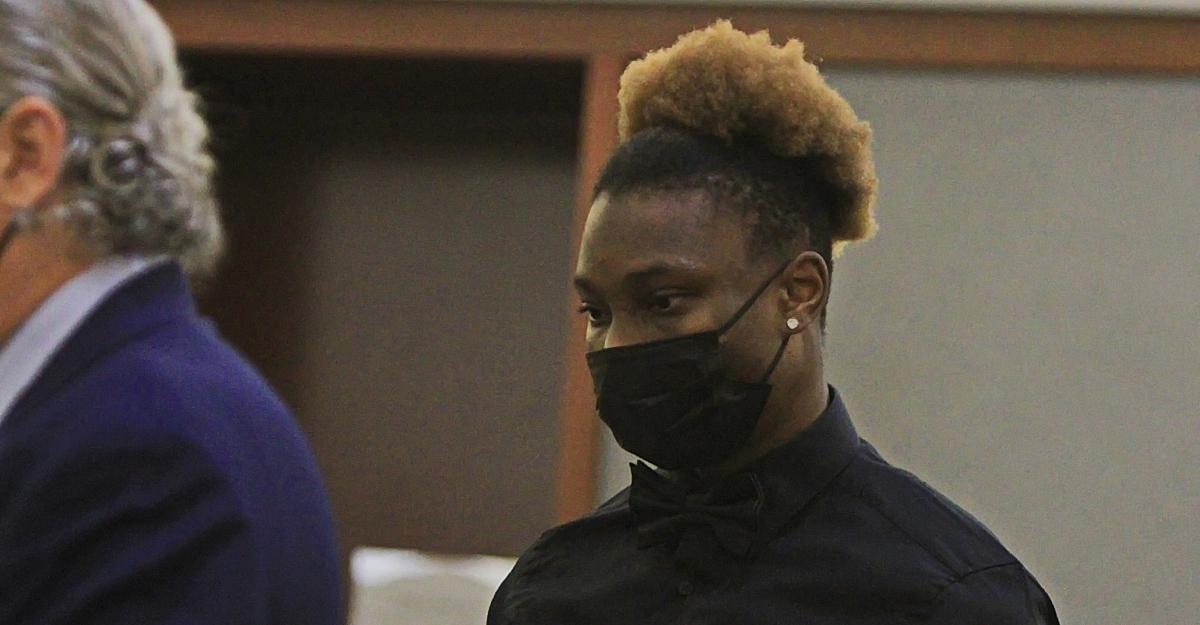 Former NFL wide receiver Henry Ruggs stands in court, wearing a face mask.