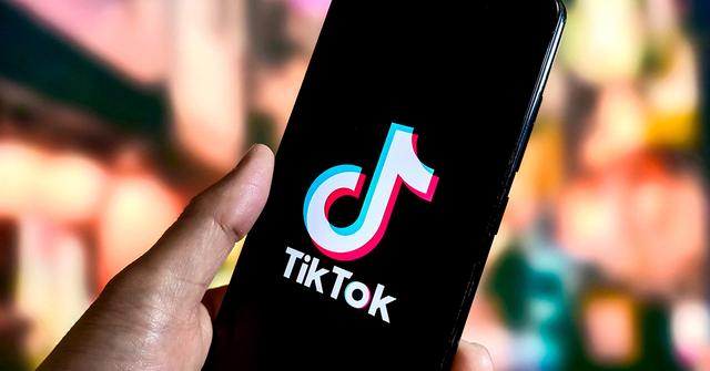 TikTok logo on a phone screen with a thumb.