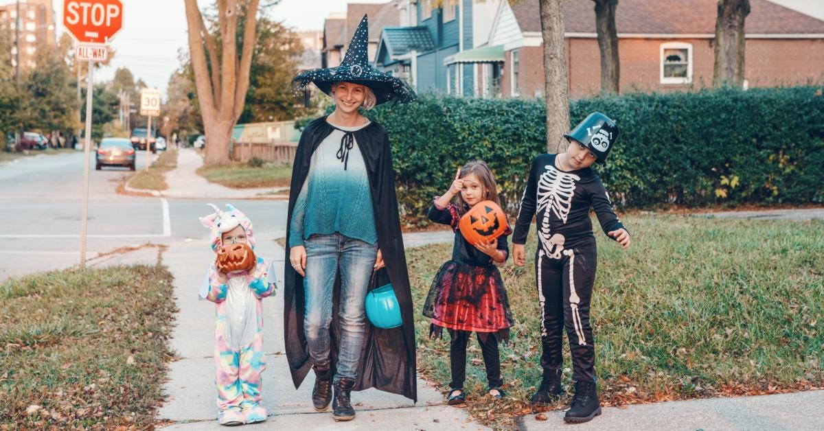 A mother takes her kids trick-or-treating on Halloween.