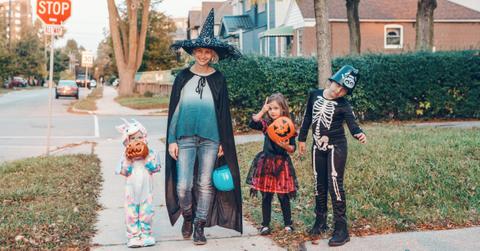 A mother takes her kids trick-or-treating on Halloween.