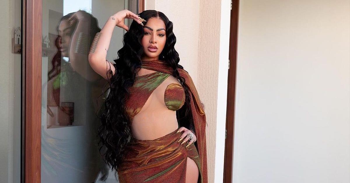 Yailin La Más Viral wearing a maroon, green, and yellow two-piece dress