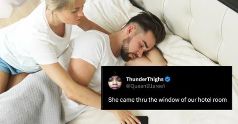 A woman reaching to check her partner's phone while he's asleep