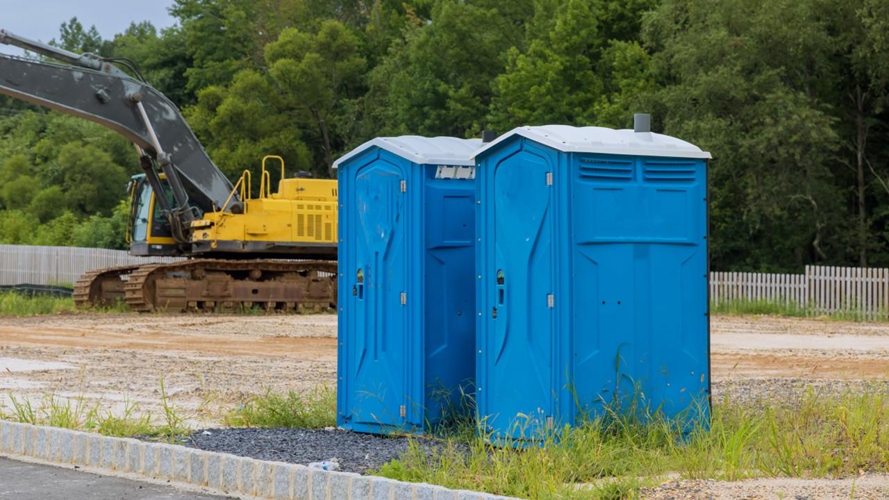 Two blue porta potties at a construction site
