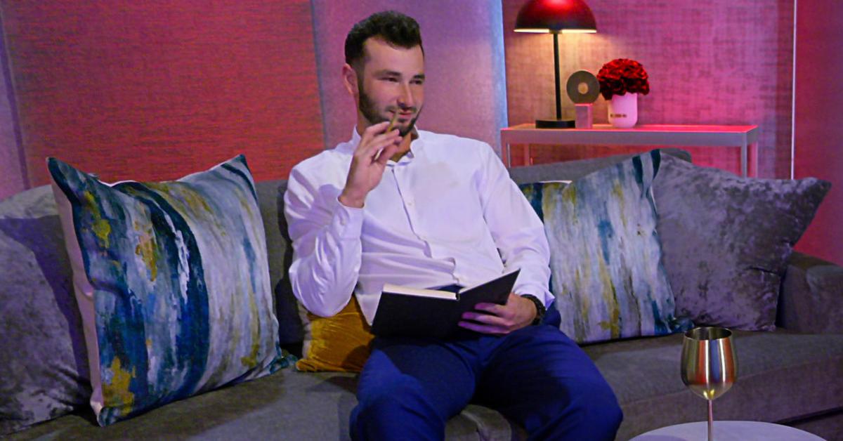 Nick sits on a couch in the 'Love Is Blind' pods.