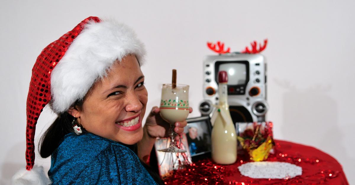 Woman Grinning While Holding a Cup of Eggnog