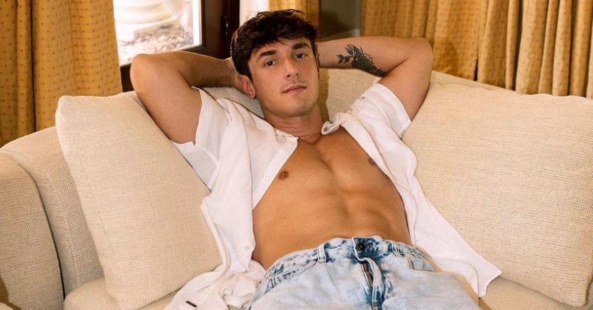 Bryce Hall laying on his couch with his short unbuttoned.